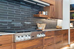 Kitchen view of wood finish cabinetry, tasteful backsplash, and stainless steel stovetop