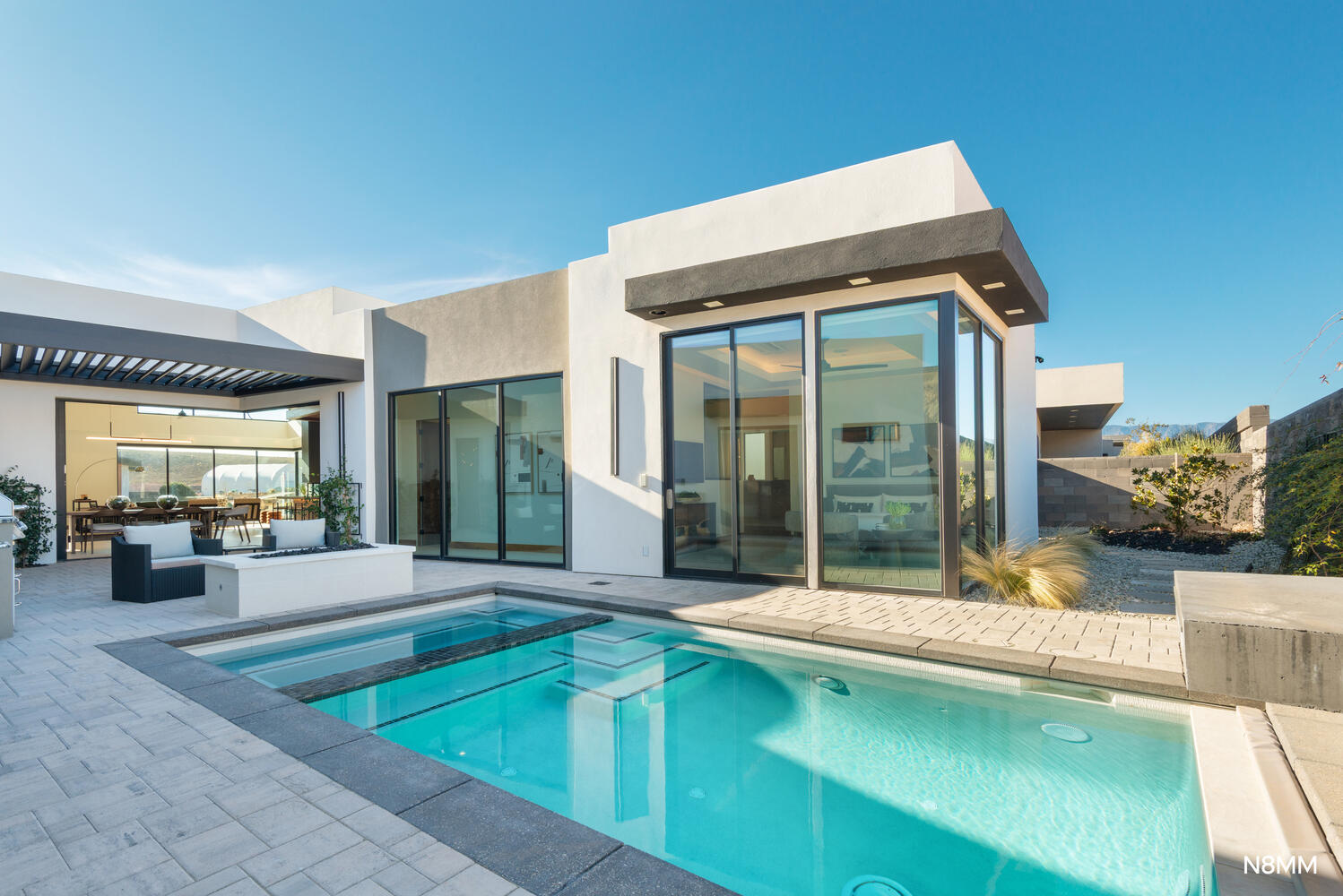 Back of property featuring a patio area, a pool with connected hot tub, and stucco siding