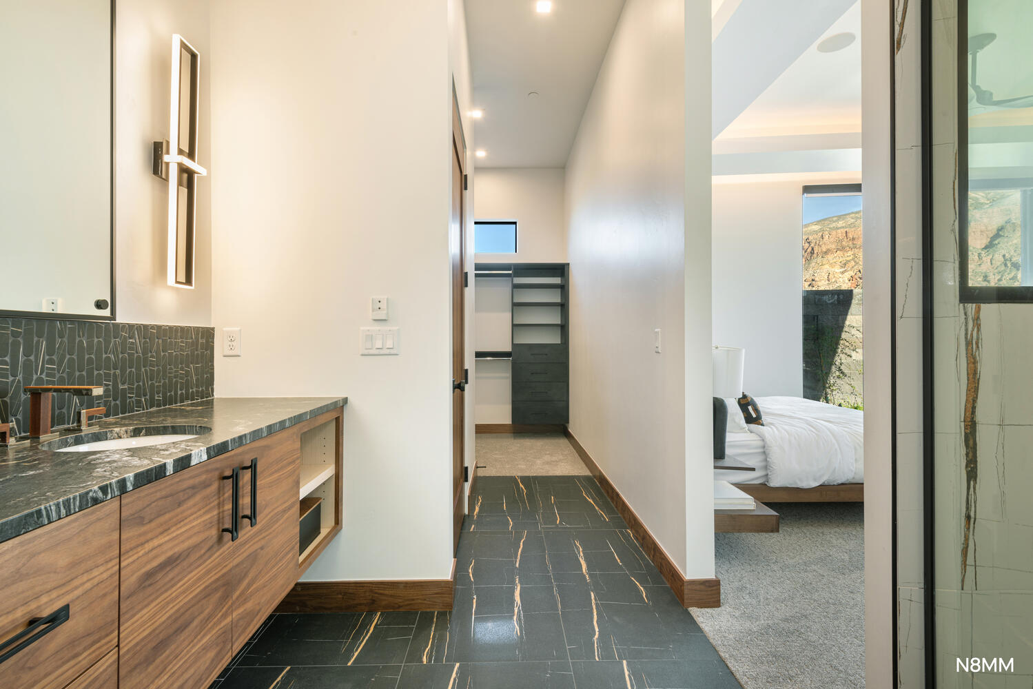 Primary full bathroom featuring vanity, ensuite bath, a walk-in closet, tasteful backsplash, and statement lighting