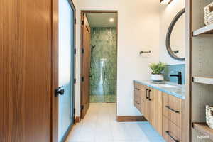 Bathroom with vanity, a tile shower, and light tile patterned floors