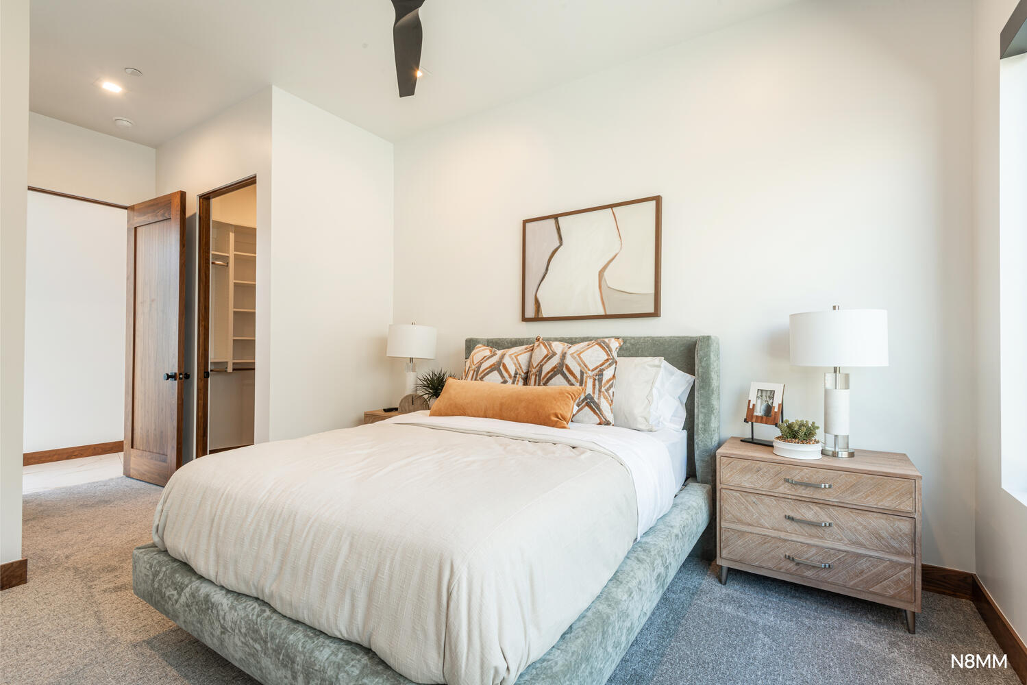 Guest bedroom with a walk-in closet, carpet floors, and a ceiling fan