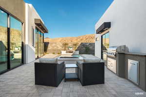 Fenced backyard with a mountain view, a patio area, a fire pit, and exterior kitchen