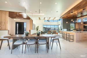 Dining area with beamed ceiling, light flooring, and stylish lighting.