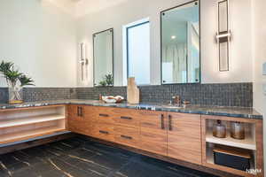 Bathroom featuring double vanity and tasteful backsplash