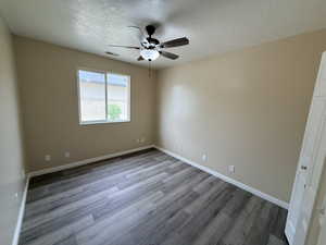 Spare room featuring ceiling fan, light wood finished floors, and a textured ceiling