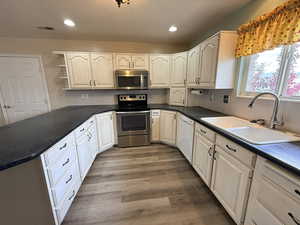 Kitchen featuring stainless steel appliances, dark countertops, open shelves, recessed lighting, and dark wood-style floors