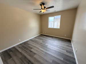 Empty room featuring light wood-style flooring, ceiling fan, and a textured ceiling