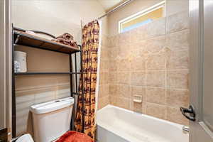 Bathroom featuring toilet and shower / tub combo with curtain
