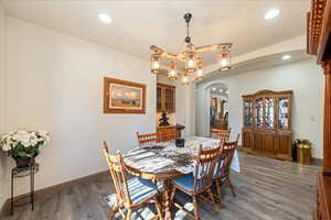 Dining room featuring arched walkways, wood finished floors, and a chandelier