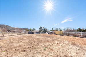 View of yard featuring an enclosed riding area, a mountain view, a view of countryside, and an outbuilding