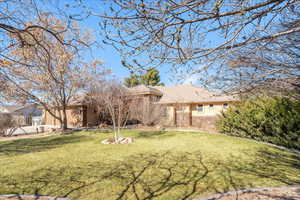 Back of house featuring a lawn, stucco siding, stone siding, and a tiled roof