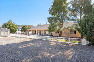 View of front of home with a fenced front yard, a storage shed, a tiled roof, stucco siding, and a patio