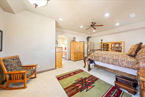 Bedroom with light colored carpet, arched walkways, recessed lighting, and a ceiling fan
