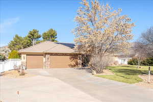 View of front facade with solar panels, concrete driveway, an attached garage, a tile roof, and stone siding