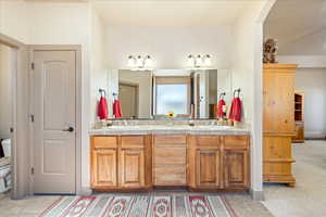 Full bath with double vanity and light colored carpet