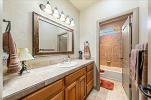 Bathroom featuring vanity, washtub / shower combination, and light tile patterned floors