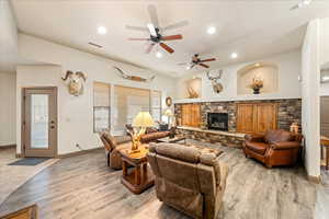 Living area with a fireplace, ceiling fan, light wood finished floors, and recessed lighting