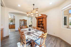 Dining space featuring arched walkways, dark wood finished floors, and recessed lighting
