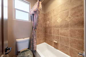 Full bath featuring toilet and shower / bathtub combination with curtain