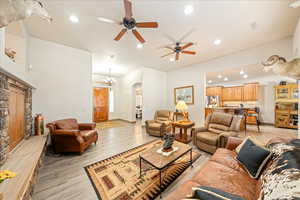 Living room with arched walkways, light wood-style floors, a ceiling fan, and suspended lighting