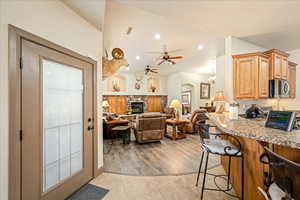 Kitchen featuring a kitchen breakfast bar, light stone countertops, arched walkways, a chandelier, and stainless steel microwave