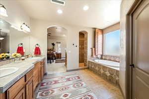 Bathroom featuring a garden tub, double vanity, walk in shower, recessed lighting, and ceiling fan