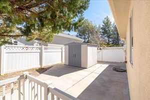 Fenced backyard featuring a storage shed and a patio