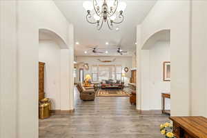 Foyer featuring arched walkways, light wood finished floors, suspended lighting, and ceiling fan