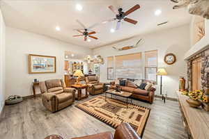 Living area with light wood-type flooring, a ceiling fan, recessed lighting, and a fireplace