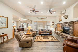 Living area featuring wood finished floors, a stone fireplace, ceiling fan, and recessed lighting