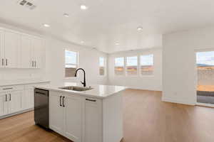 Kitchen with light wood finished floors, white cabinetry, stainless steel dishwasher, and recessed lighting