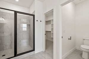 Bathroom featuring a shower stall, a spacious closet, and light tile patterned floors