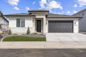 Prairie-style house featuring stucco siding, stone siding, driveway, and an attached garage