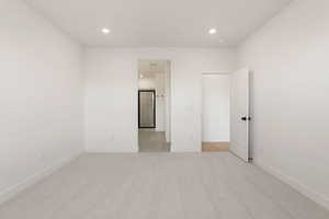 Unfurnished bedroom with light colored carpet and recessed lighting