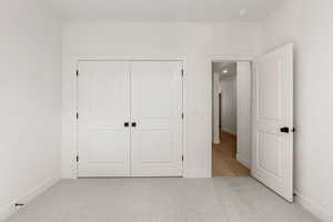 Unfurnished bedroom with light colored carpet and a closet