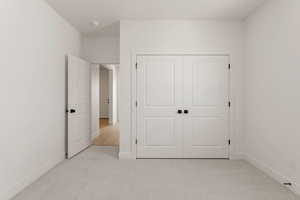 Unfurnished bedroom featuring light colored carpet and a closet