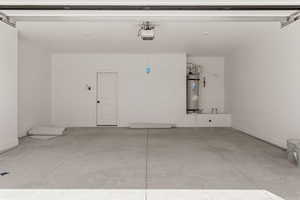 Garage featuring secured water heater and a garage door opener
