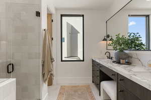 Bathroom with double vanity, a stall shower, and healthy amount of natural light