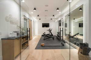 Exercise area featuring a barn door, light wood-style floors, and recessed lighting