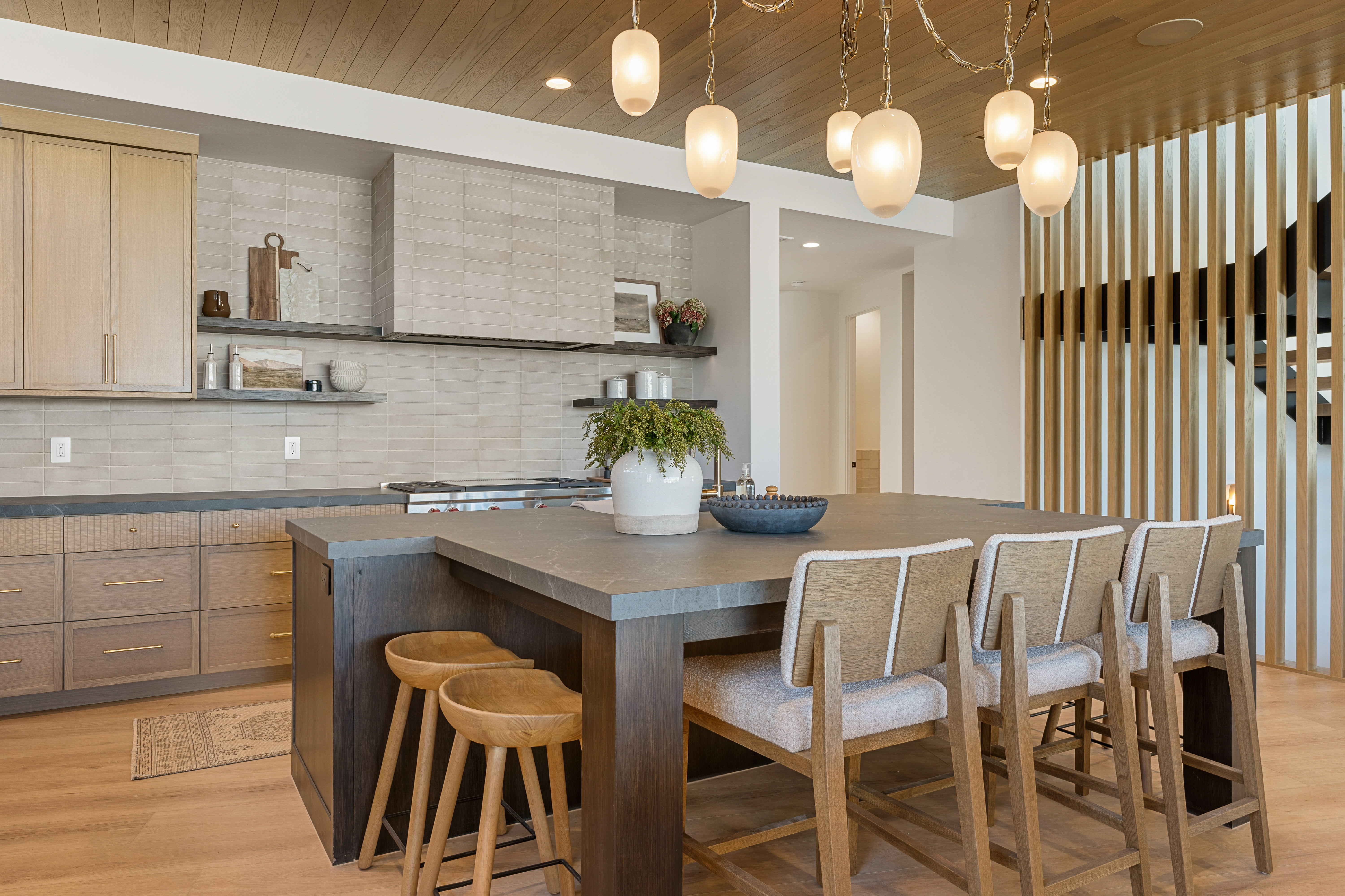 Kitchen with dark countertops, light wood-type flooring, open shelves, a kitchen bar, and wood ceiling