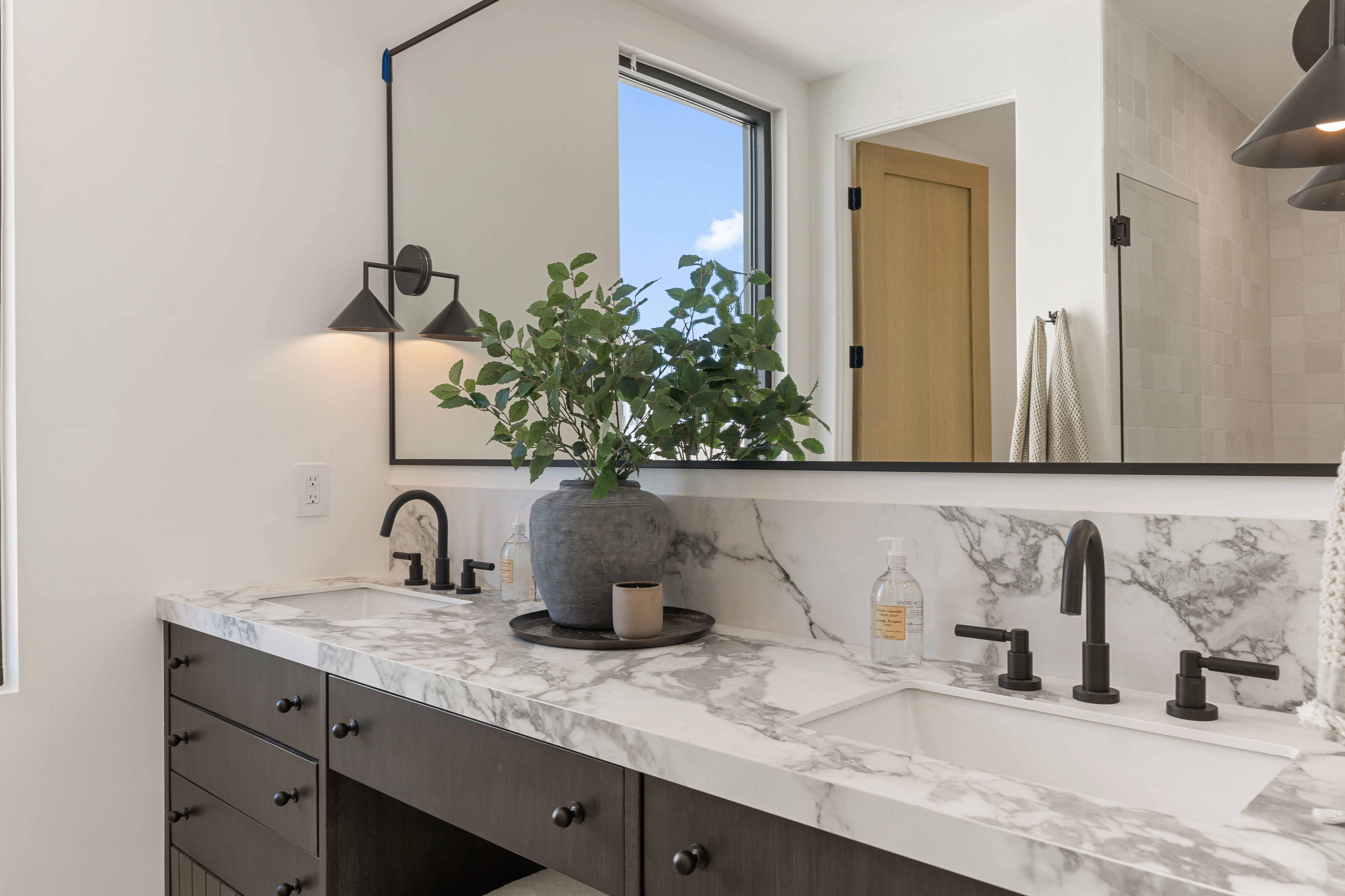 Bathroom with double vanity, backsplash, and tiled shower