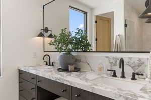 Bathroom with double vanity, backsplash, and tiled shower