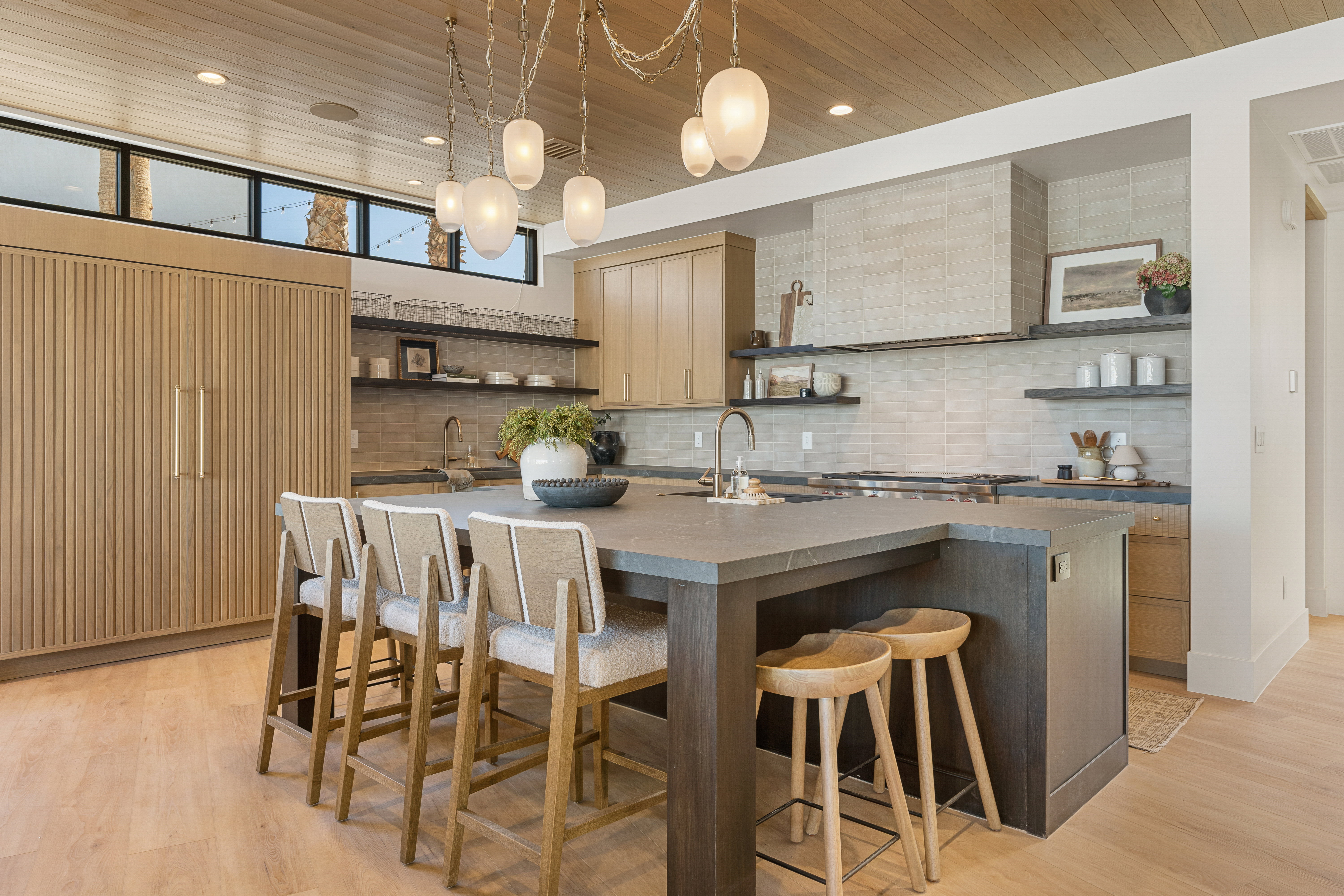 Kitchen with open shelves, a center island with sink, light wood-type flooring, a kitchen bar, and wooden ceiling