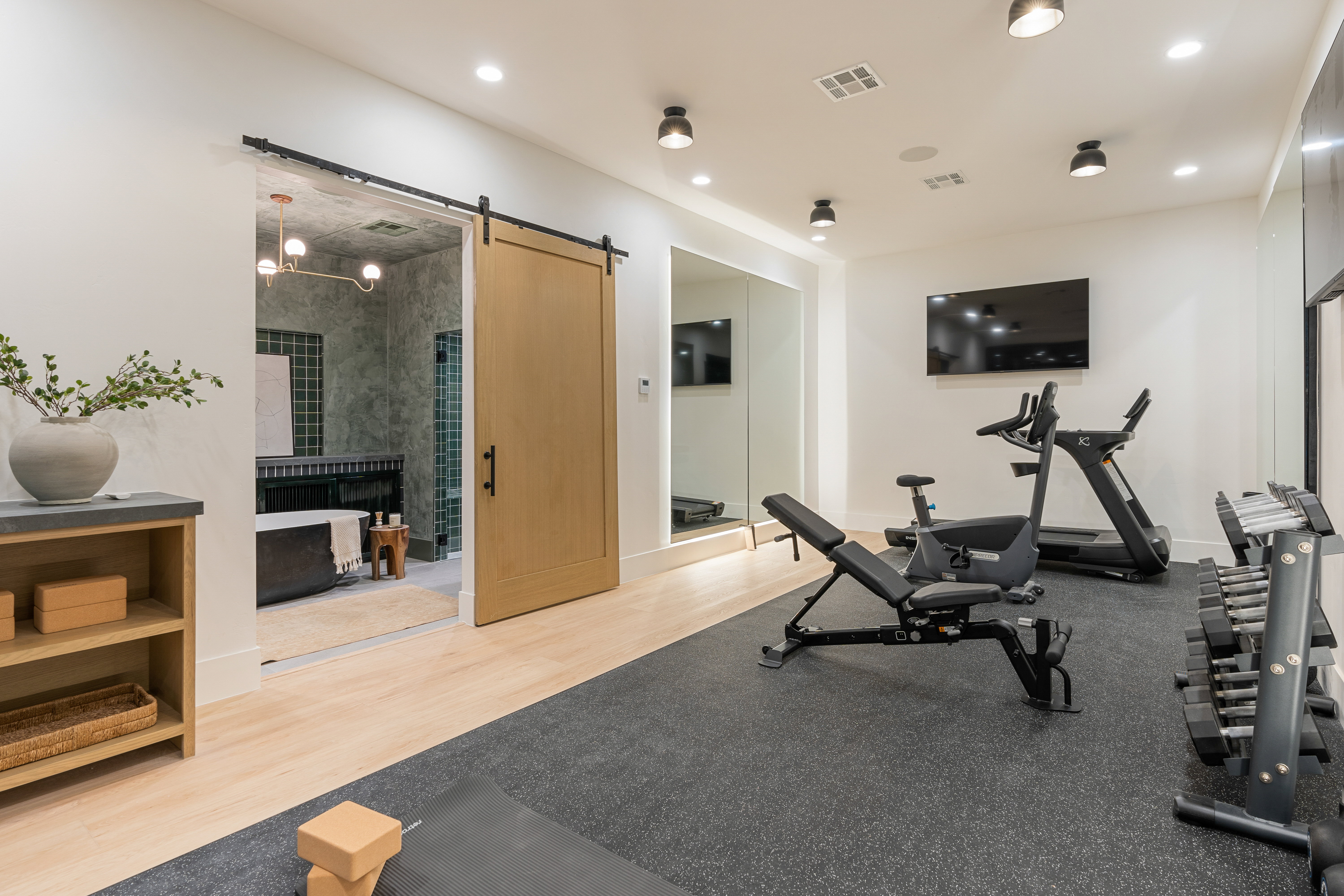 Exercise area with a barn door, light wood-type flooring, and recessed lighting