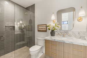 Bathroom featuring a shower stall, vanity, decorative backsplash, and light tile patterned floors