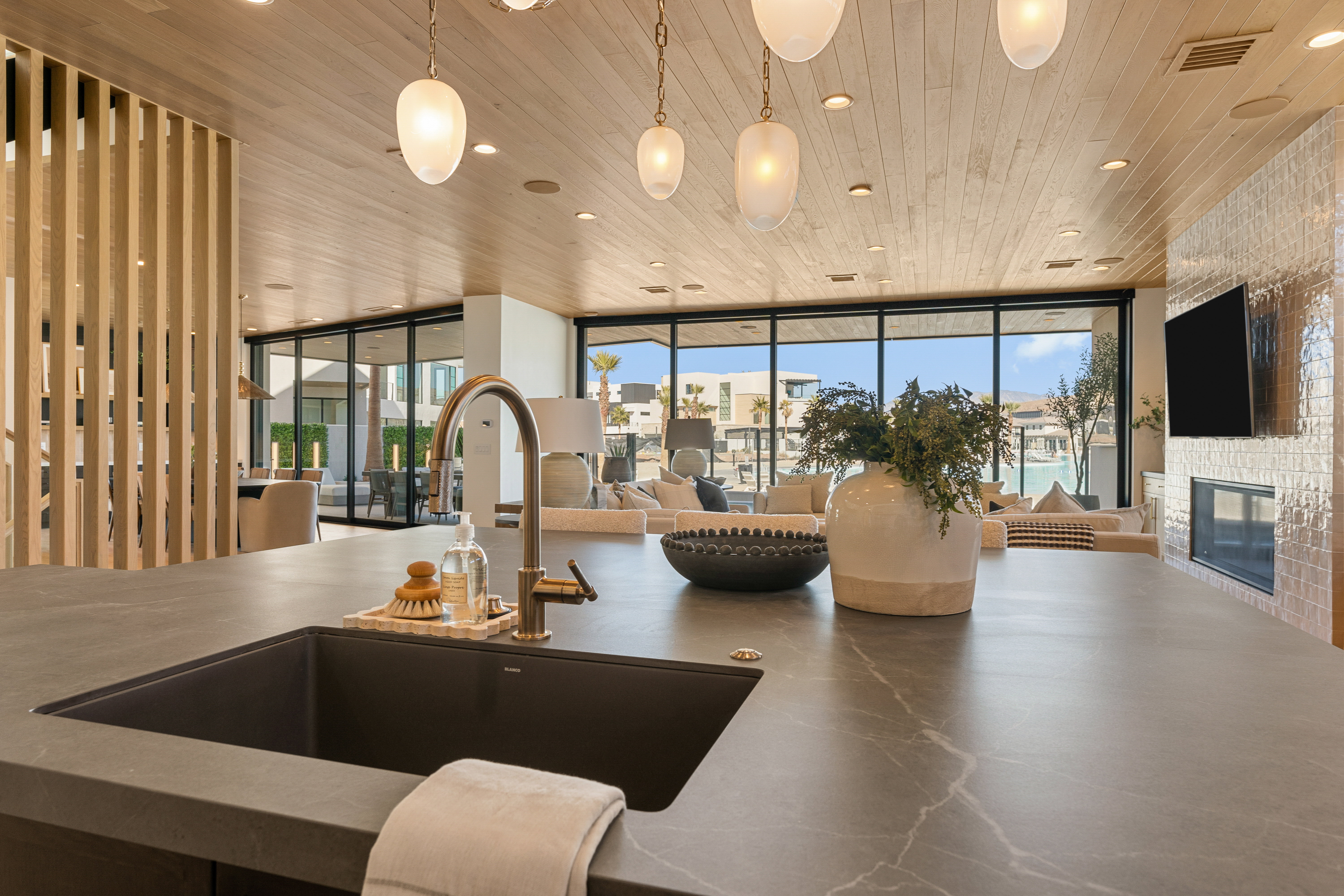 Kitchen featuring decorative light fixtures, open floor plan, wooden ceiling, a fireplace, and expansive windows