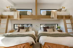Carpeted bedroom featuring multiple windows and a high ceiling