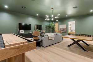 Living area with suspended lighting and light wood-style floors