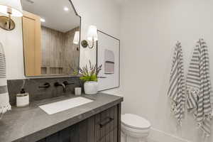 Bathroom featuring vanity, tiled shower, tasteful backsplash, and recessed lighting