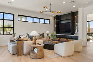 Living room featuring light wood-style floors, healthy amount of natural light, and hanging lights